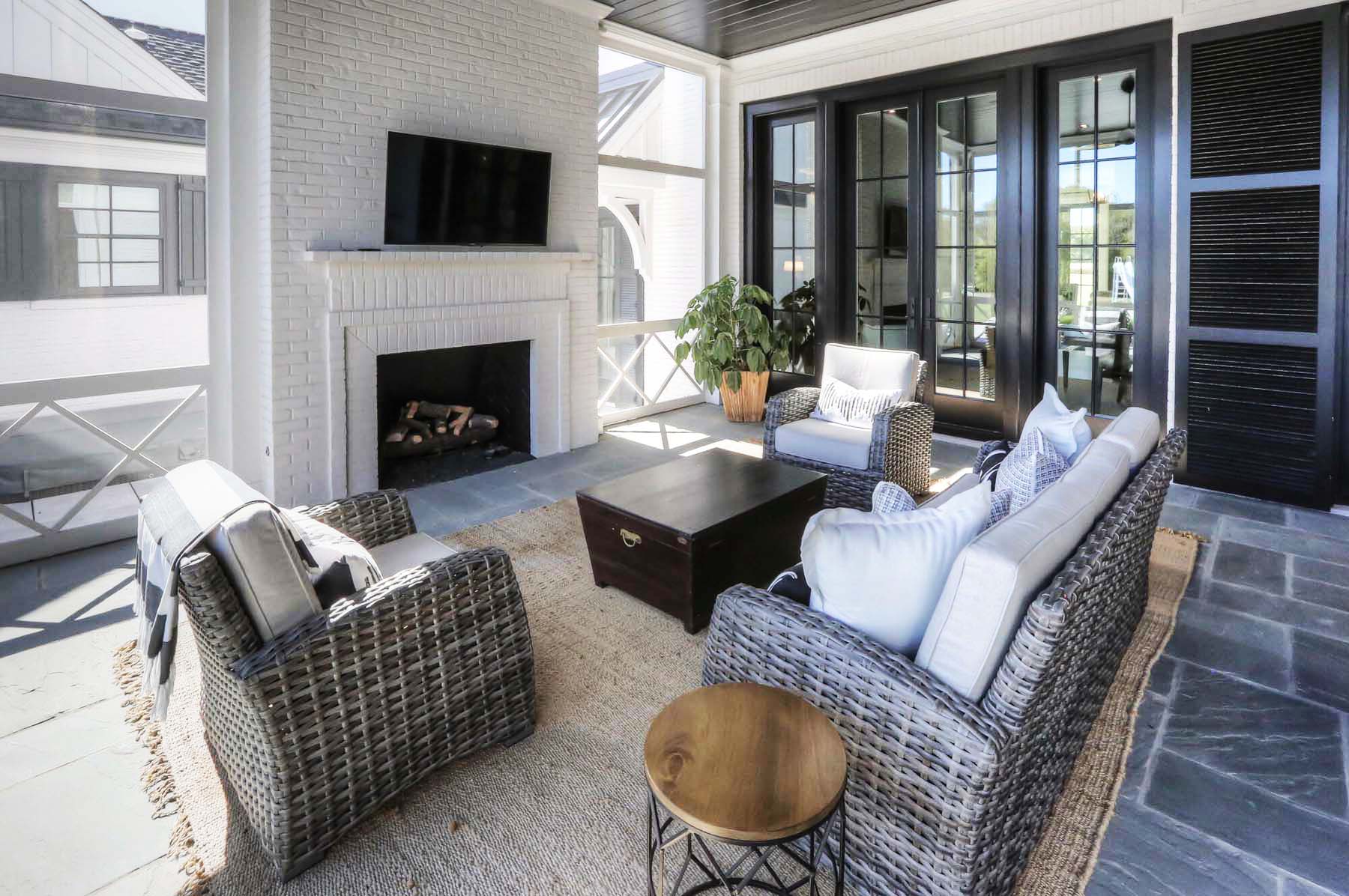 red brick outdoor fireplace painted white with TV mounted above