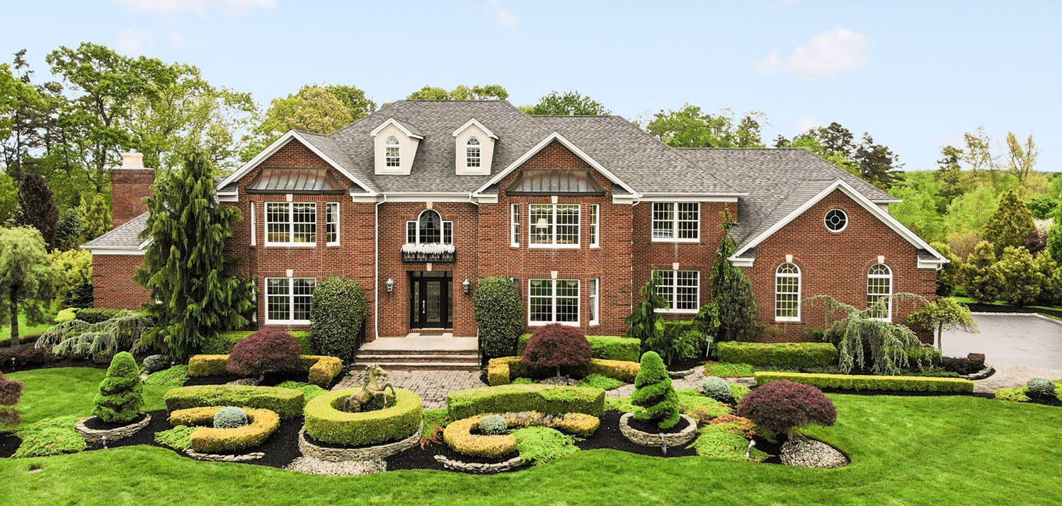 Large home with red brick veneer and black front door with glass. 