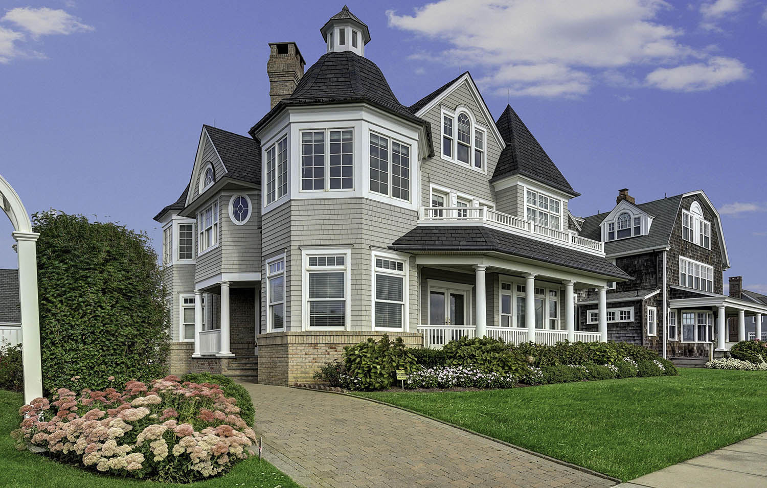 Beautiful home with gray cedar shake siding, white trim and red brick.