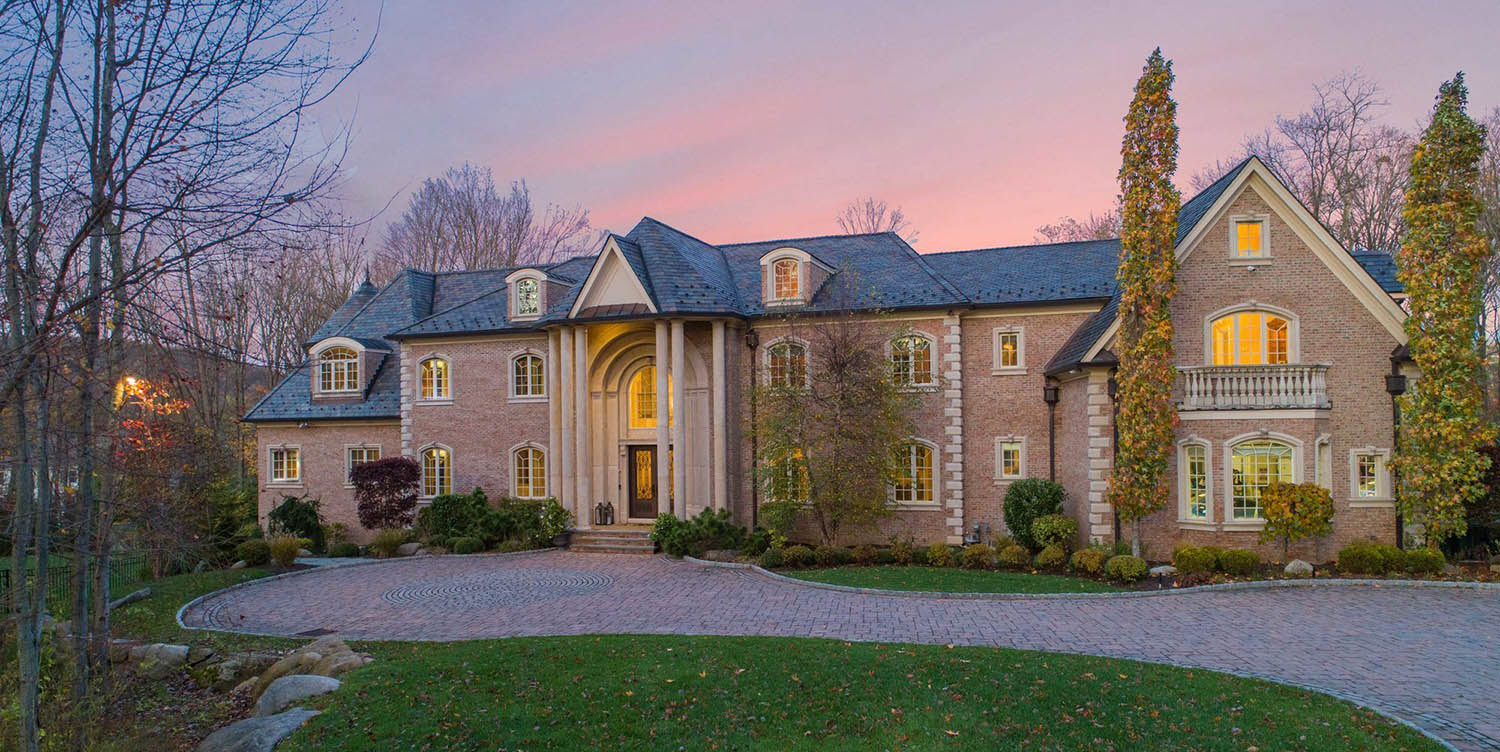 Large brick estate home with stucco accents and huge front columns.