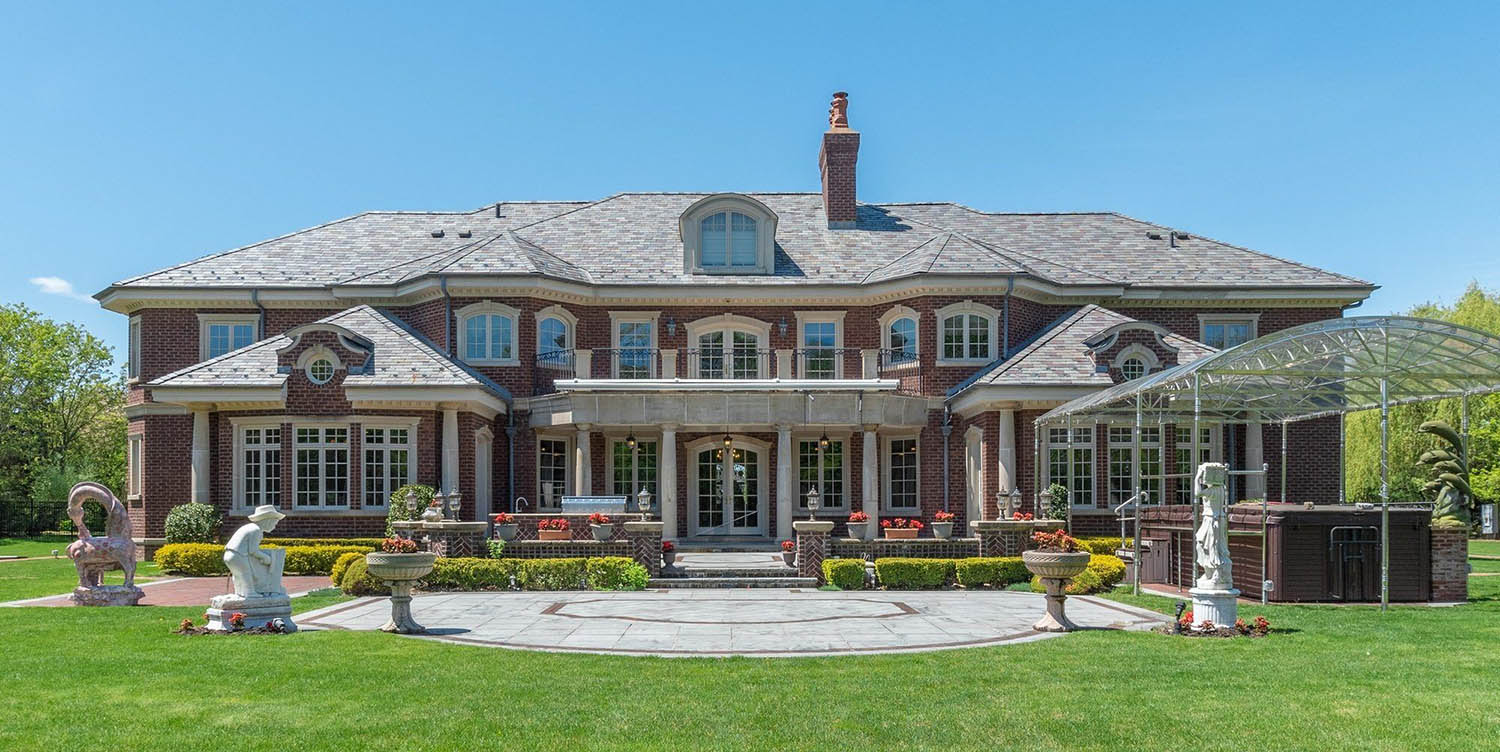 Beautiful red brick estate home with cement accents and round columns.