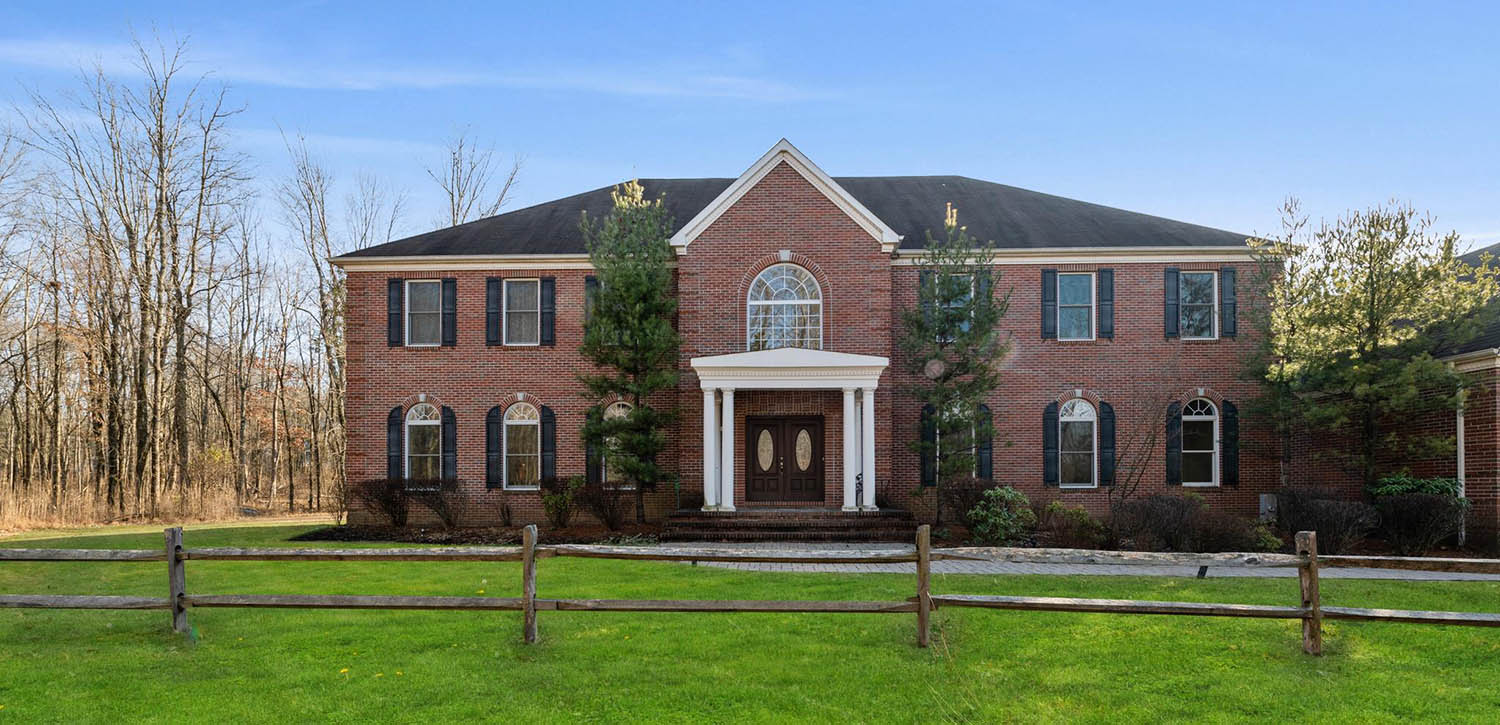 Beautiful red brick home with white front porch and columns. Dark brown front door with black shutters.