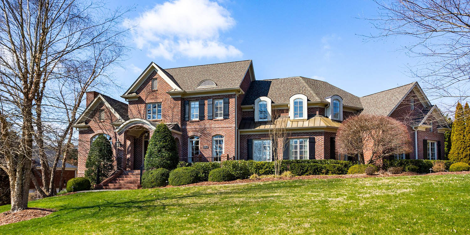 Beautiful red brick home with stucco accent and white trim. Black front door.