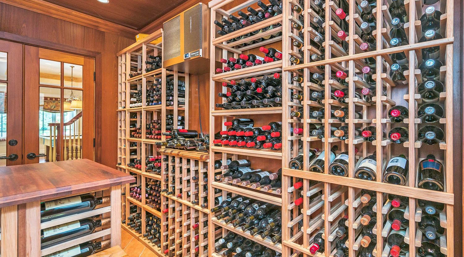 wine room with built in through the wall cooling unit and wood racks center table and lots of wine bottles