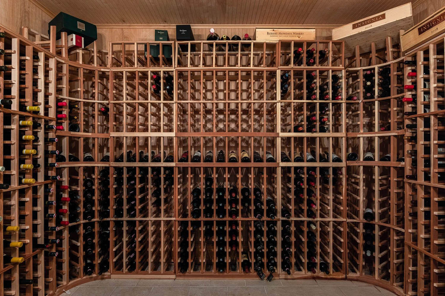 Large DIY wine room with wooden single bottle racks. Wood wall paneling.
