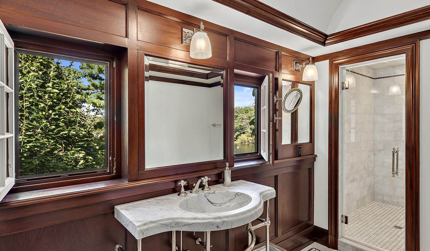 Bathroom with wood wall paneling and marble. White ceiling. Marble sink with chrome.