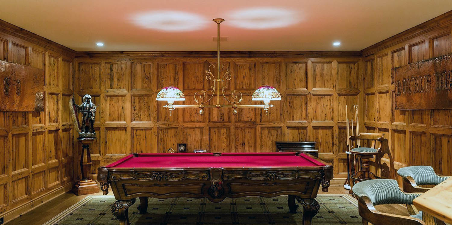 Billiard room with wood wall paneling. Beautiful wood pool table with red felt. Wood floors.