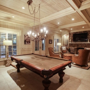 Billiard room with light wood walls and matching coffered ceiling. Tile floors.
