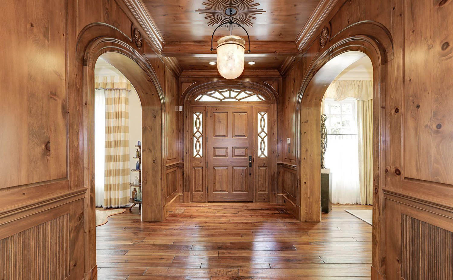 Hallway with all wood wall paneling and matching hardwood floors. Wood ceiling.
