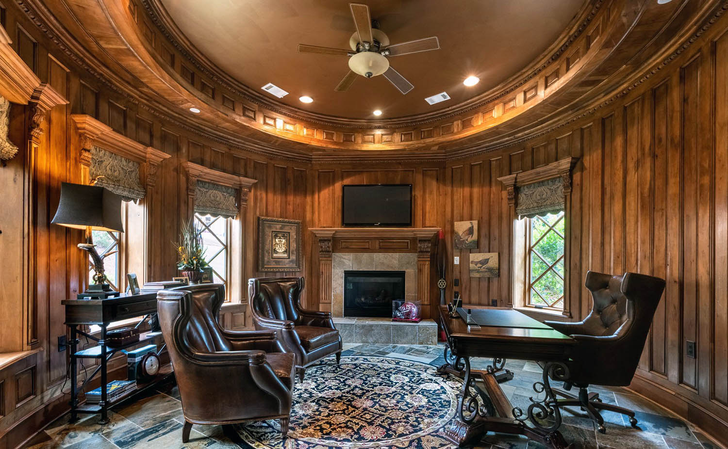 Round home office with wood wall panels and custom ceiling.