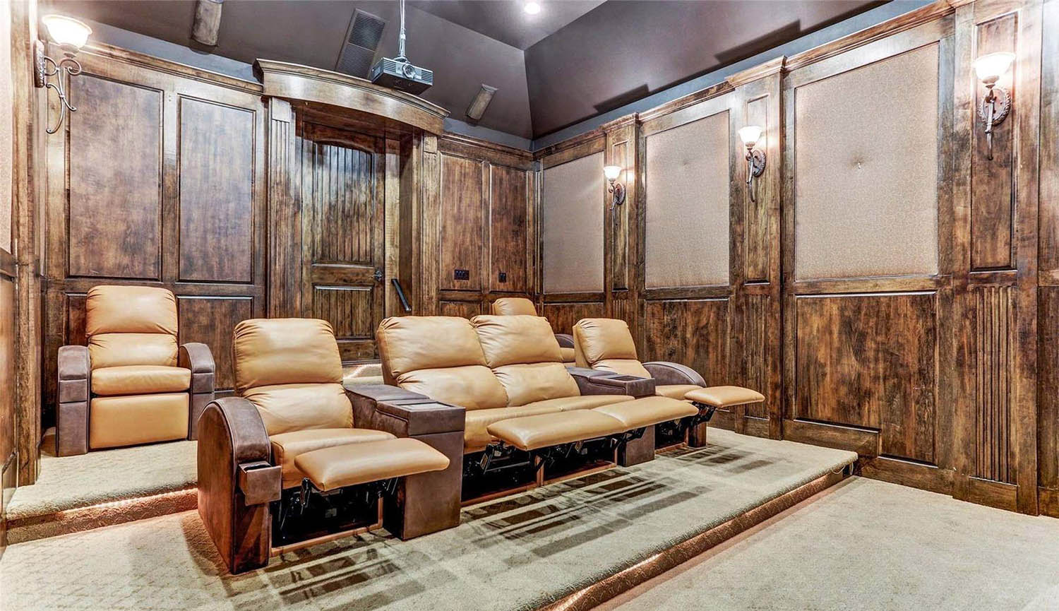 Theatre room with wood walls and carpeting. Leather recliners.