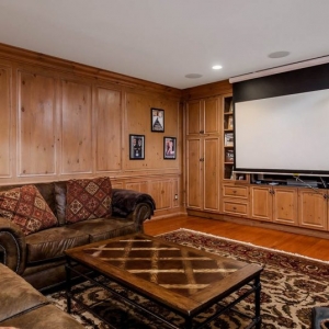 Living room with all wood wall paneling and built ins. Hardwood floors. Brown leather sofas.