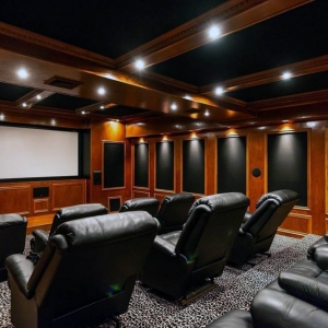Home theatre room with all wood walls and wood ceiling. Black leather recliners.
