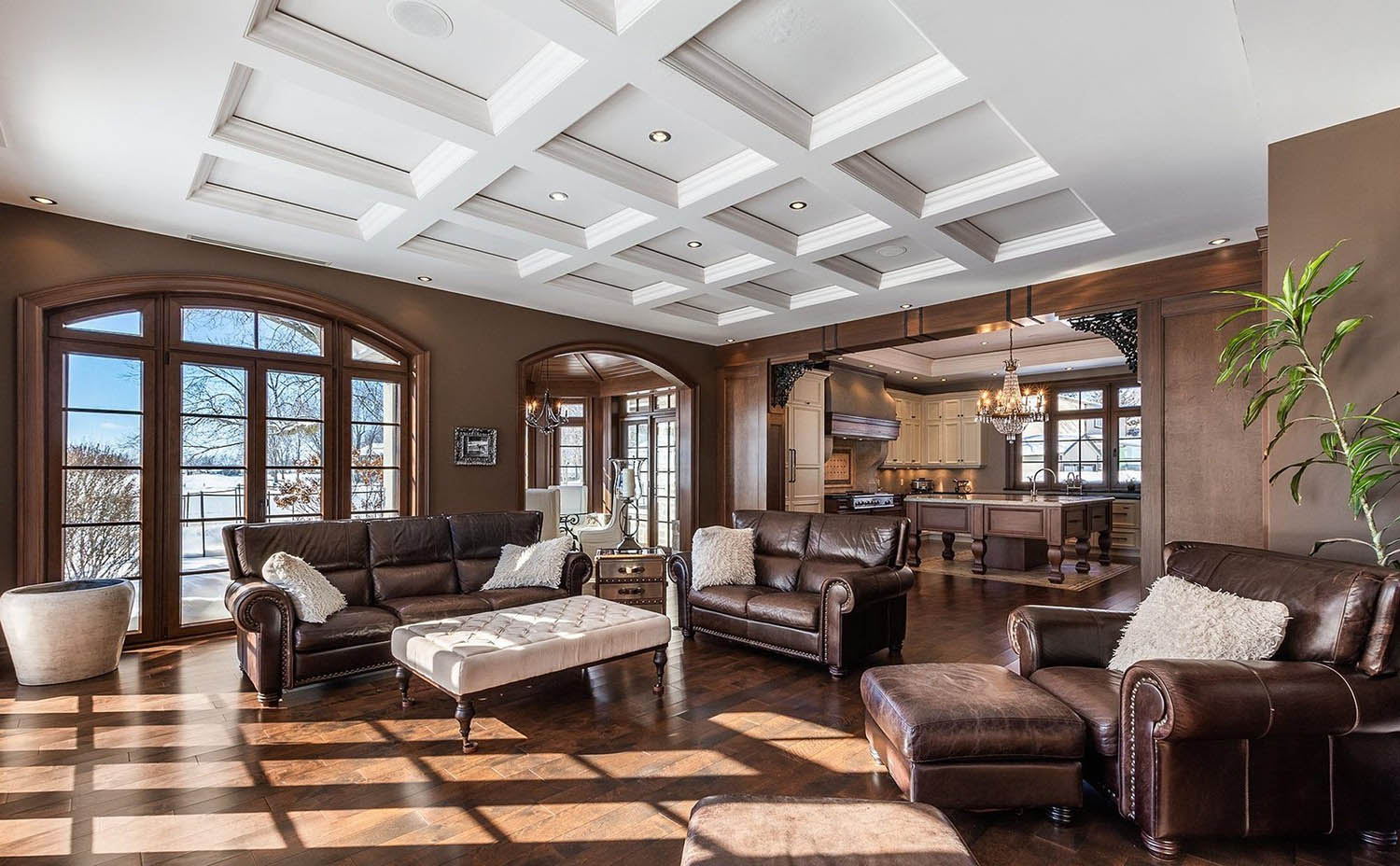 Beautiful living room with all white coffered ceiling recessed into the ceiling with soffits. Recessed LED lighting. Brown walls with brown stained trim.