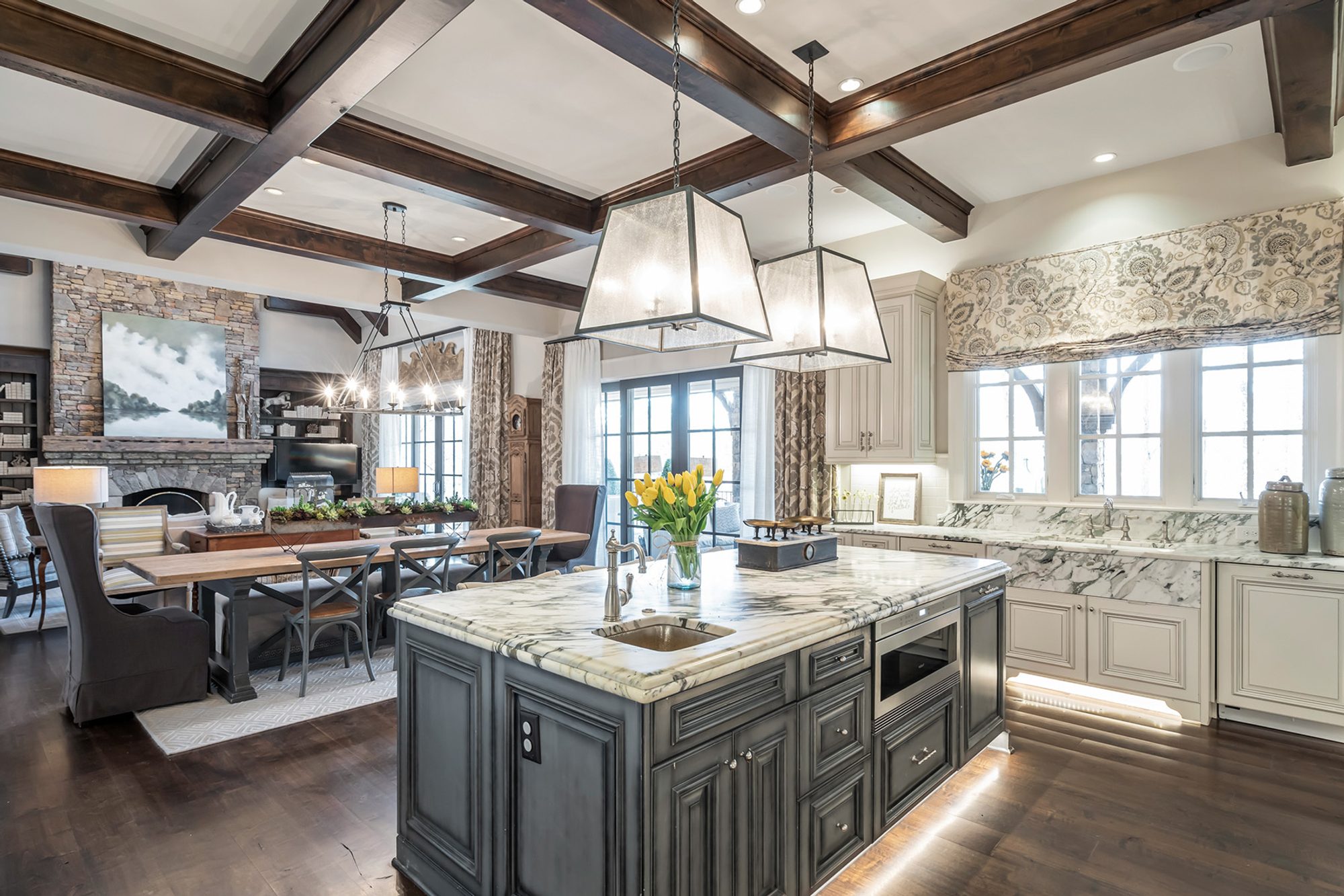 beautiful kitchen gray center island with marble countertop, dark wood stained coffered ceiling. Open floor plan.