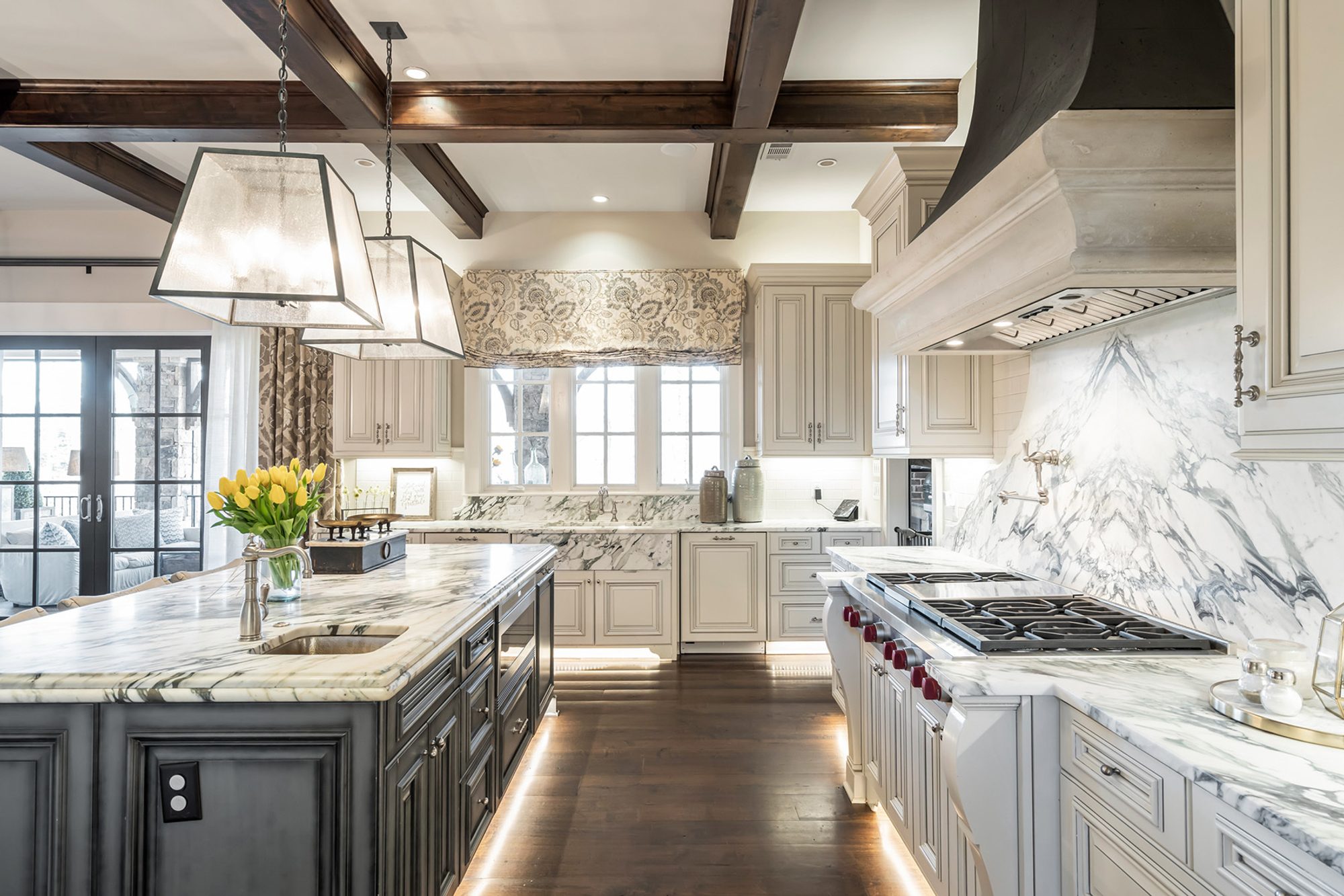 Luxury kitchen with marble slab backsplash, wolf stove, marble countertops, dark wood coffered ceiling.