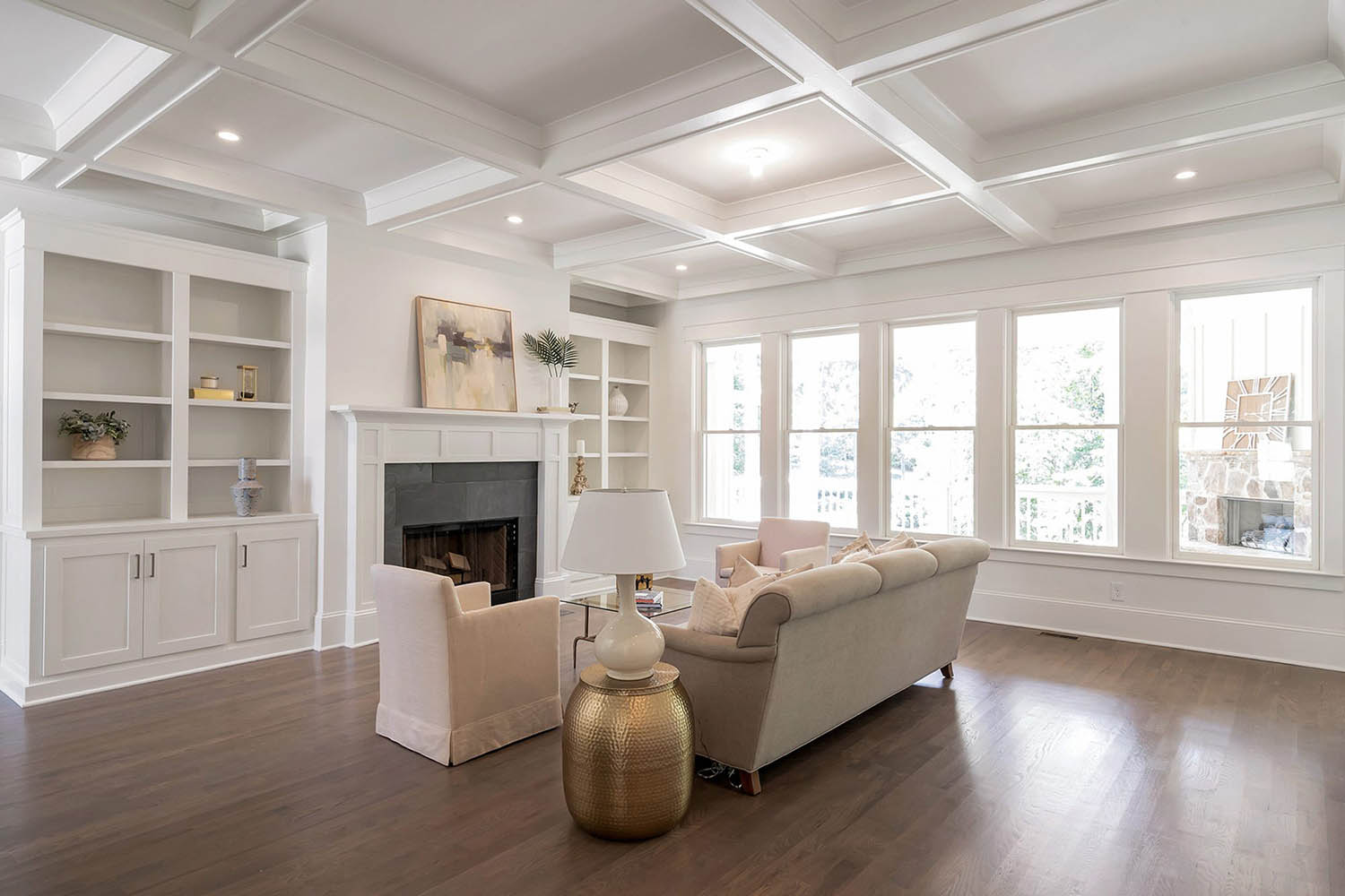 Living room coffered ceiling. White walls and ceiling. White trim and built ins with gray tile fireplace surround.