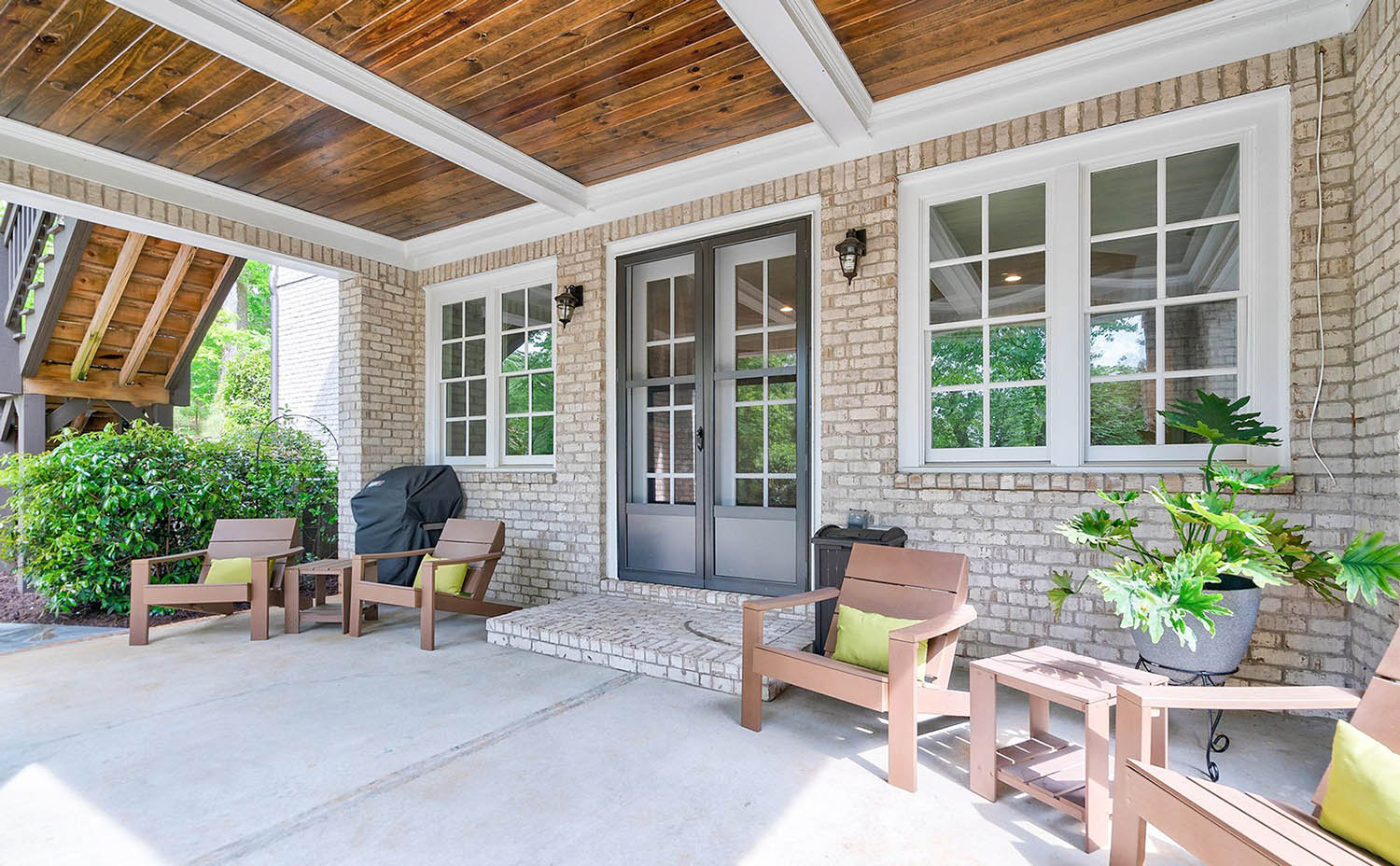 Outdoor covered patio with tan brick walls. Outdoor coffered ceiling, white beams with beadboard.