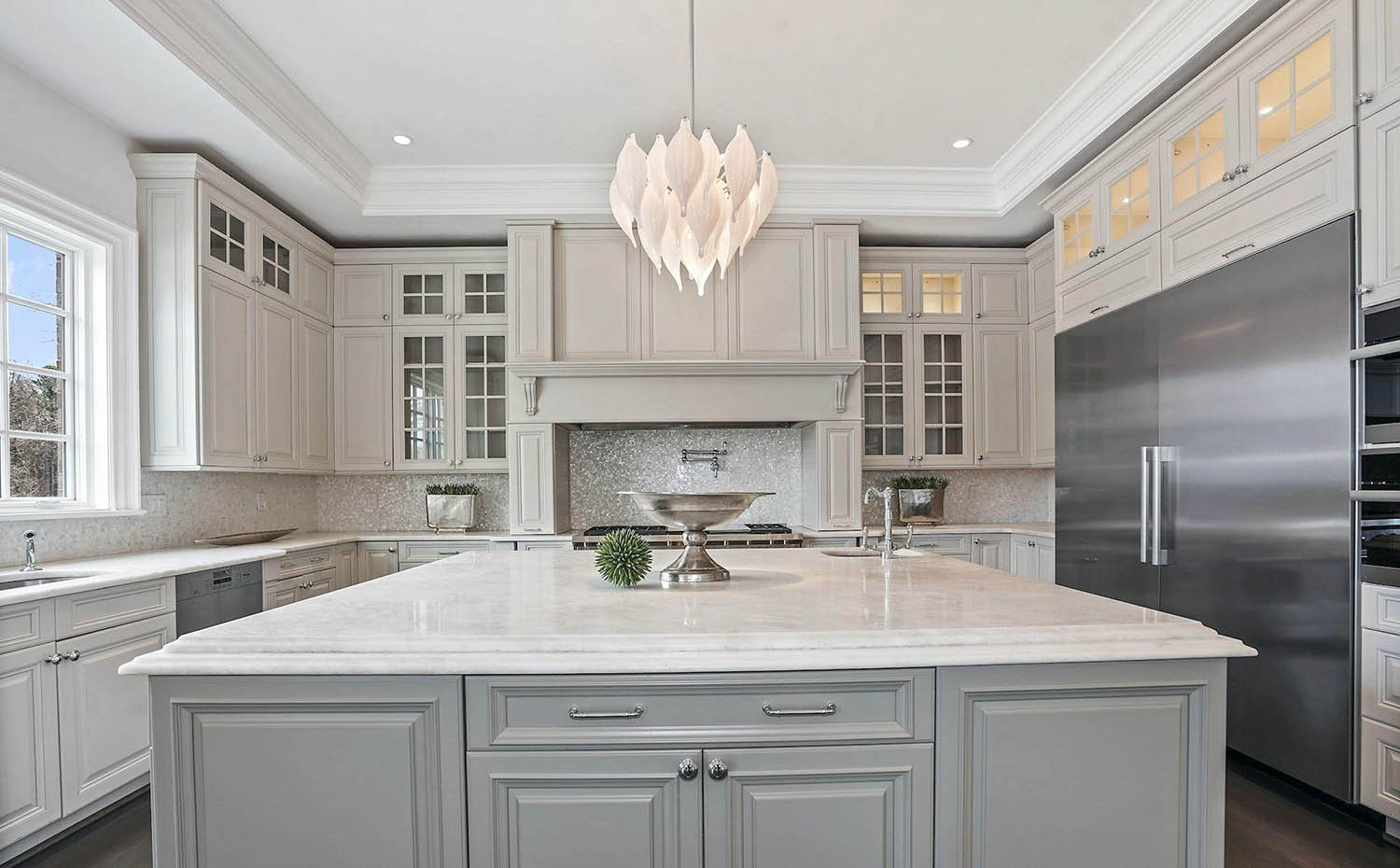 Light gray cream kitchen cabinets with a slightly darker gray island. Marble countertops.