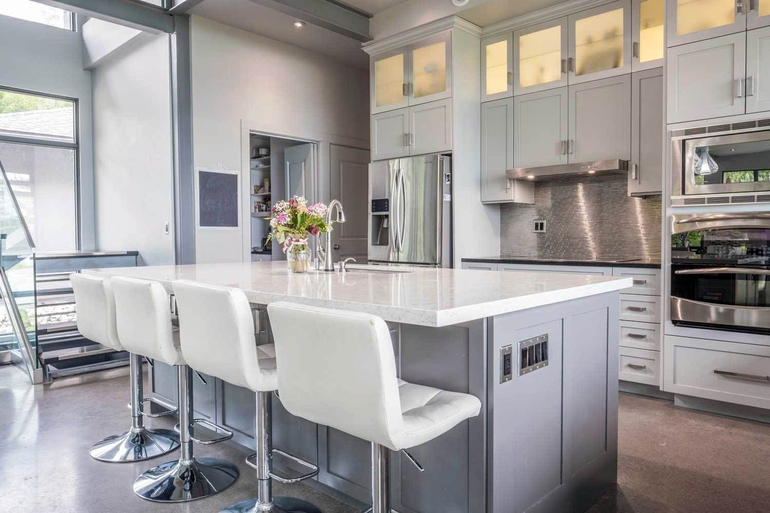 Modern kitchen design featuring cream colored cabinets. Marble countertops.