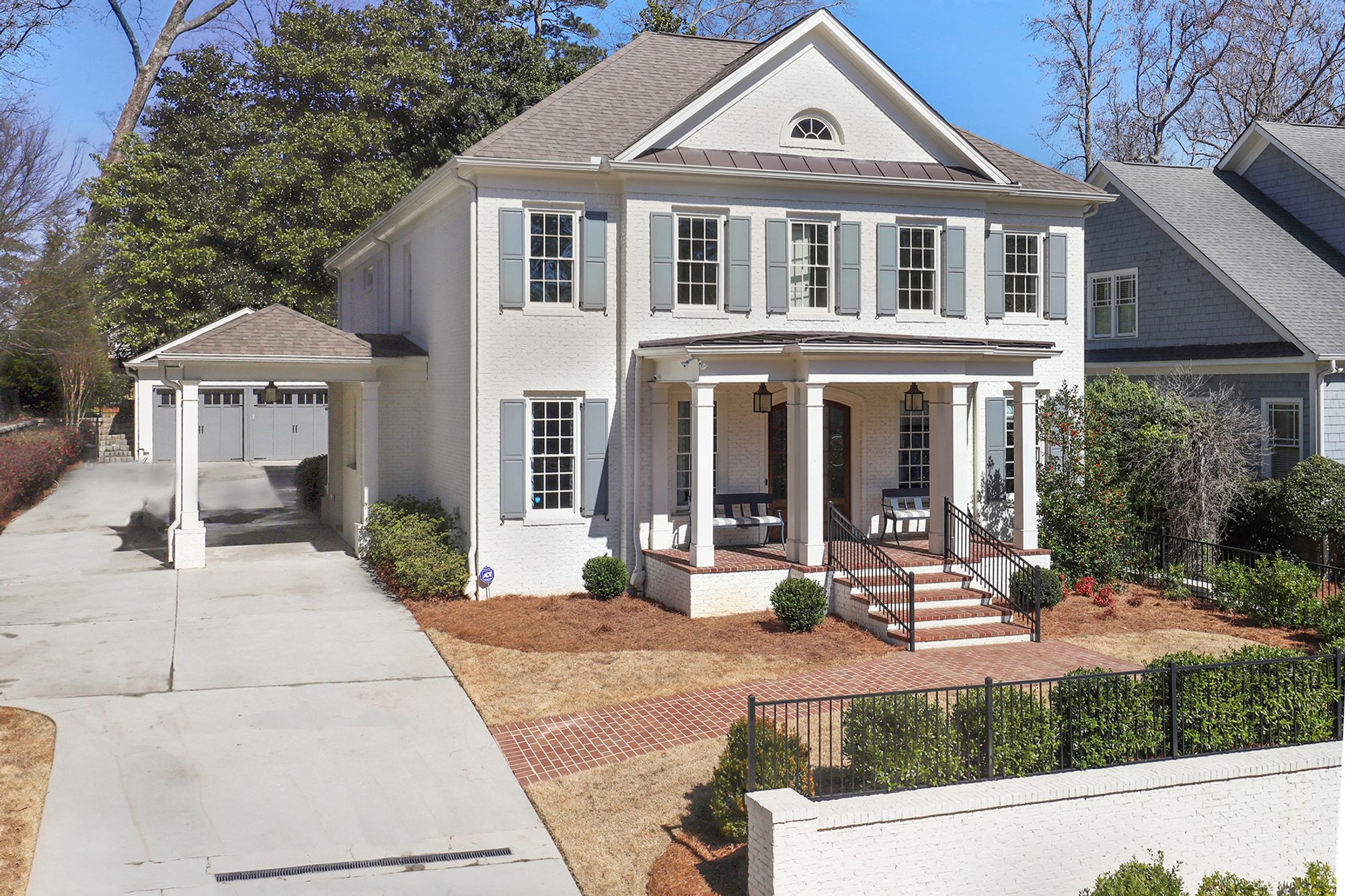 Beautiful white brick house with red brick front porch, steps and walkway. Detached white brick garage. Blue shutters and matching garage doors. Arched top wood front door.