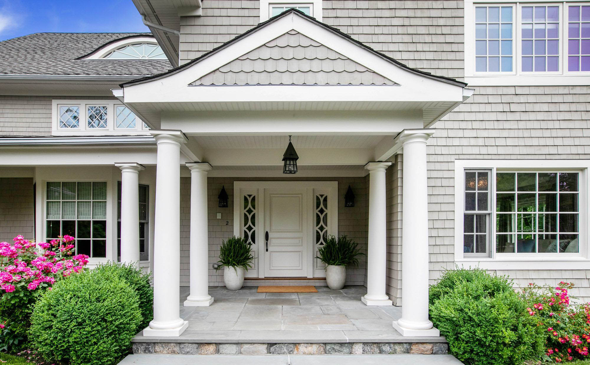 white front door with white side by side planters, white columns and trim, bluestone porch top, landscaping