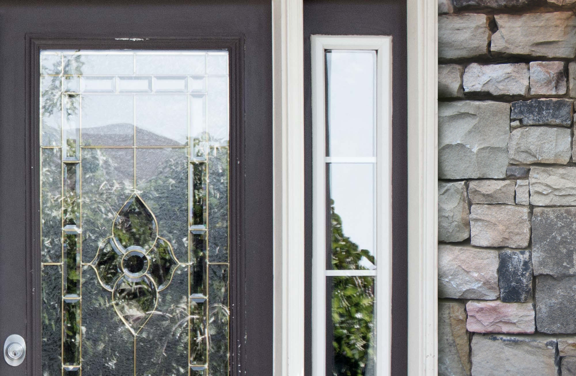 dark gray front door with gray stone veneer,sidelights and white trim 