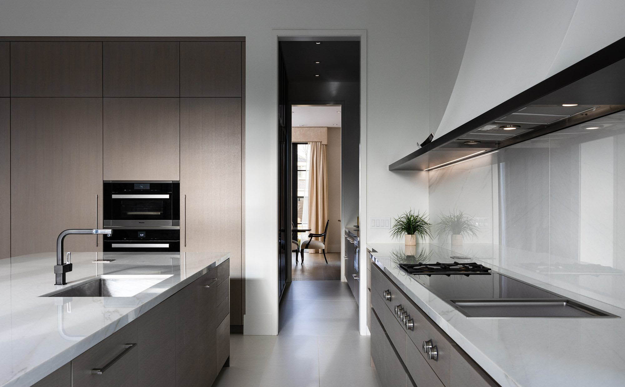 Modern kitchen with white quartz counters and matching backsplash. Muted brown gray cabinets. Super clean design. quartz vs granite.