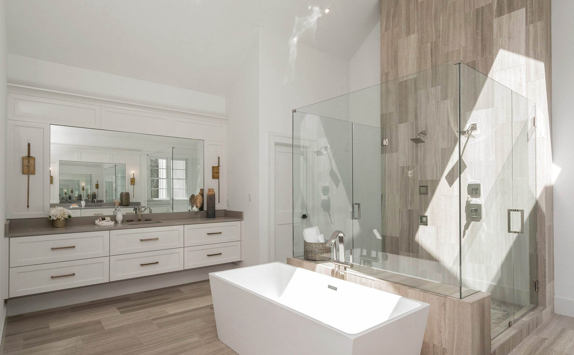 Light gray woo look bathroom floor tile with matching shower wall with glass.