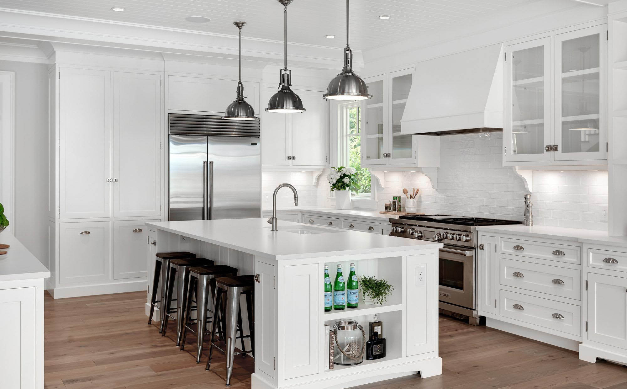 Luxury kitchen with a light knotty pine wood look flooring tile. White cabinets with white countertops.