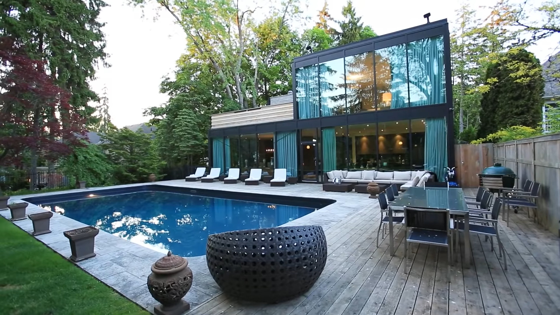This black modern home has a flat roof with rooftop deck and walls of glass.