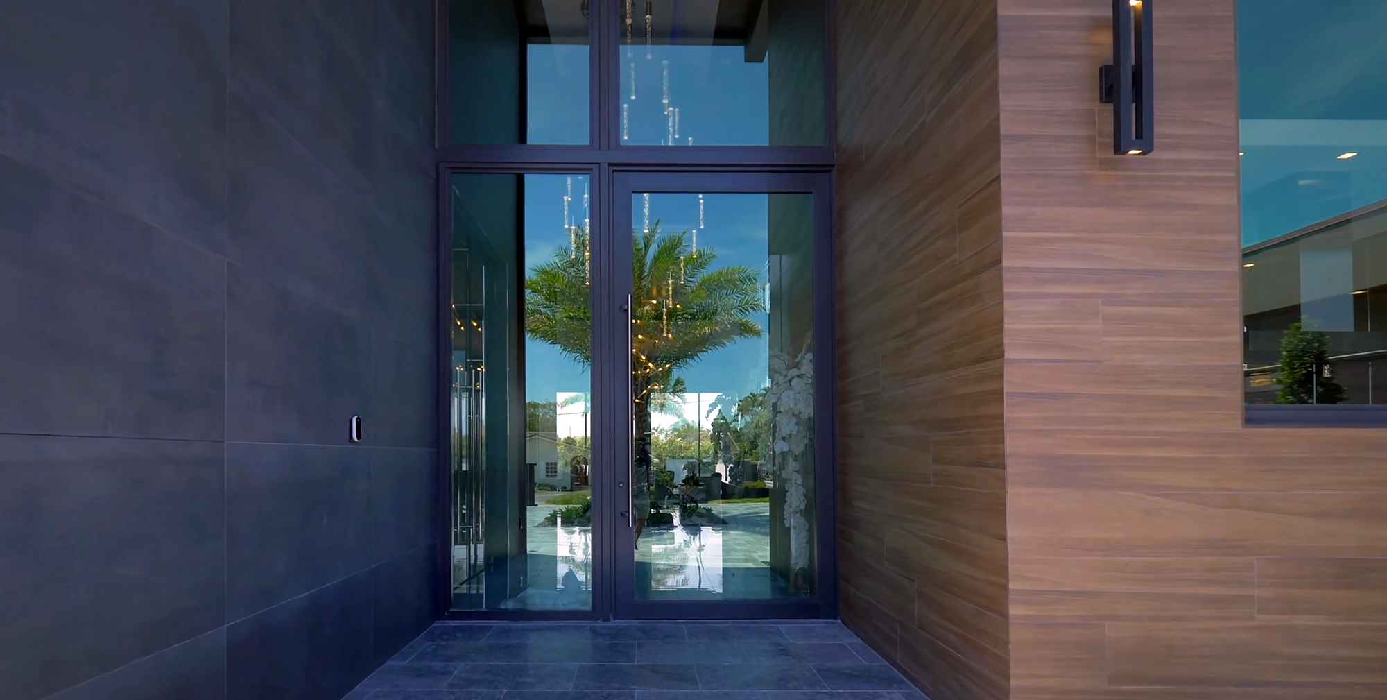 Modern Glass front door set into a glass wall with side light and transoms.