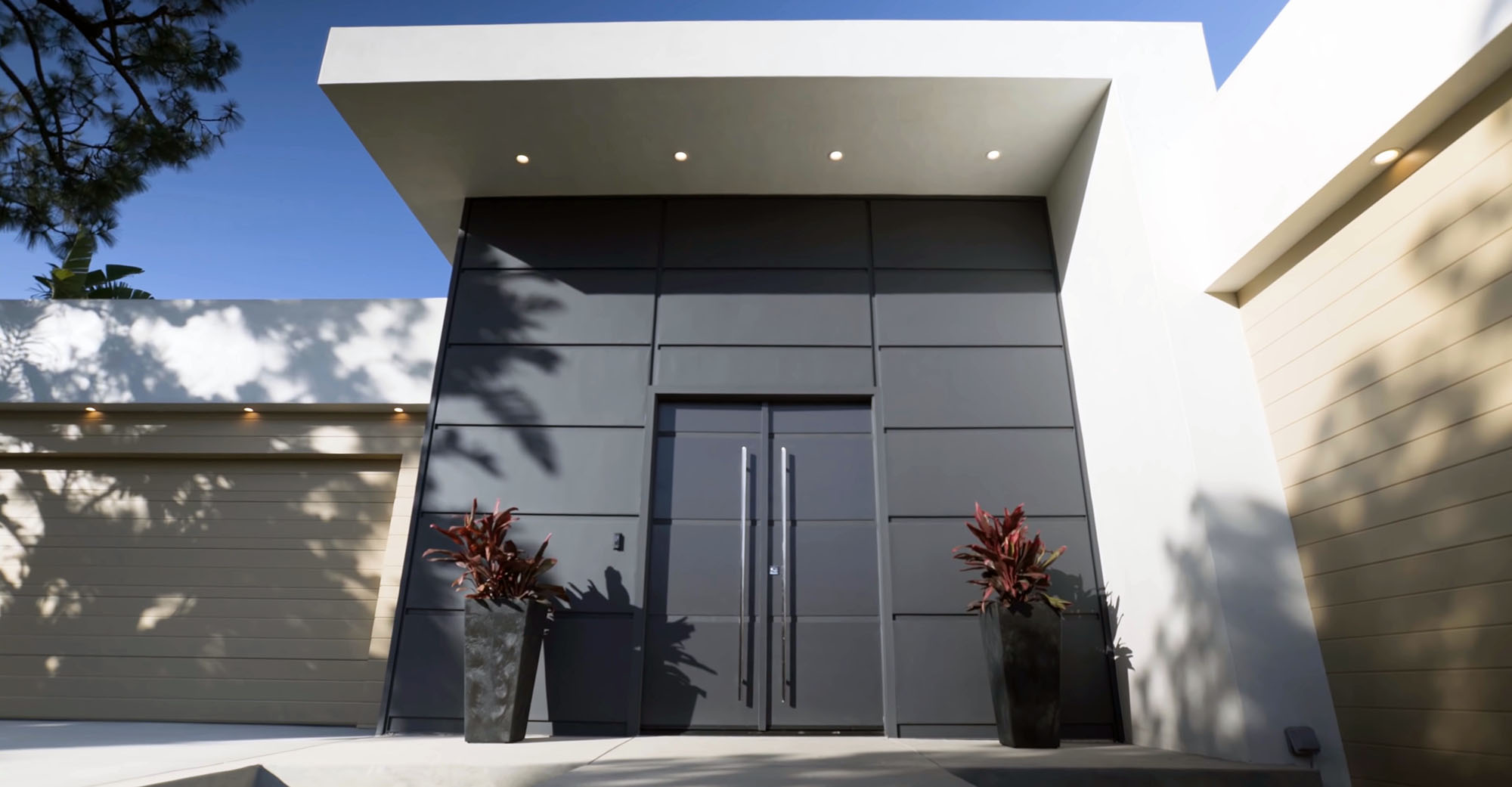 Modern front door with a monochromatic dark gray color matching the surrounding walls.