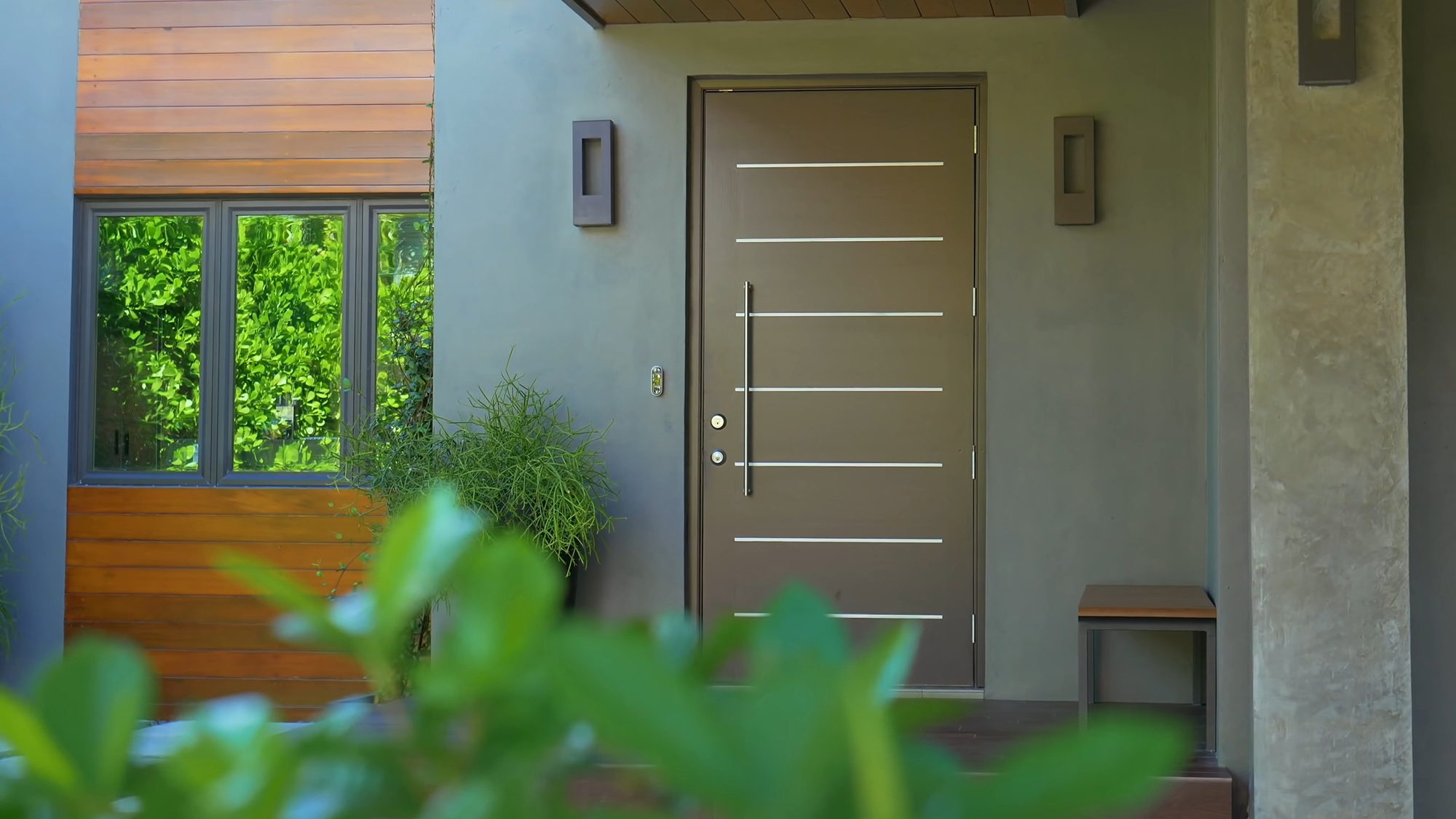 Modern taupe front door with horizontal metallic strips.