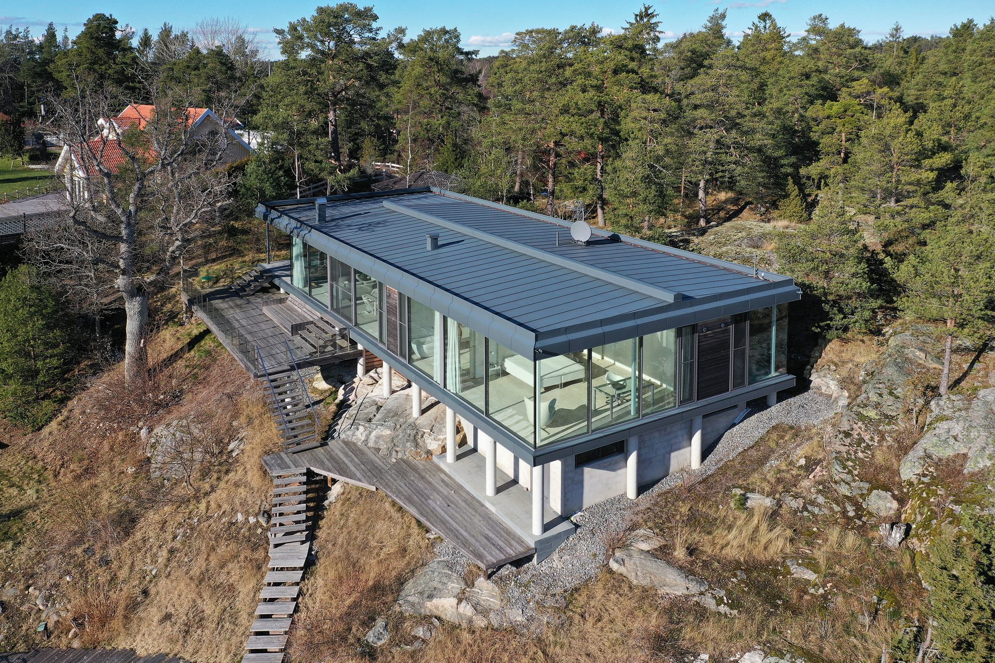 Modern metal and glass home built into the side of a rocky hill with wood decks.