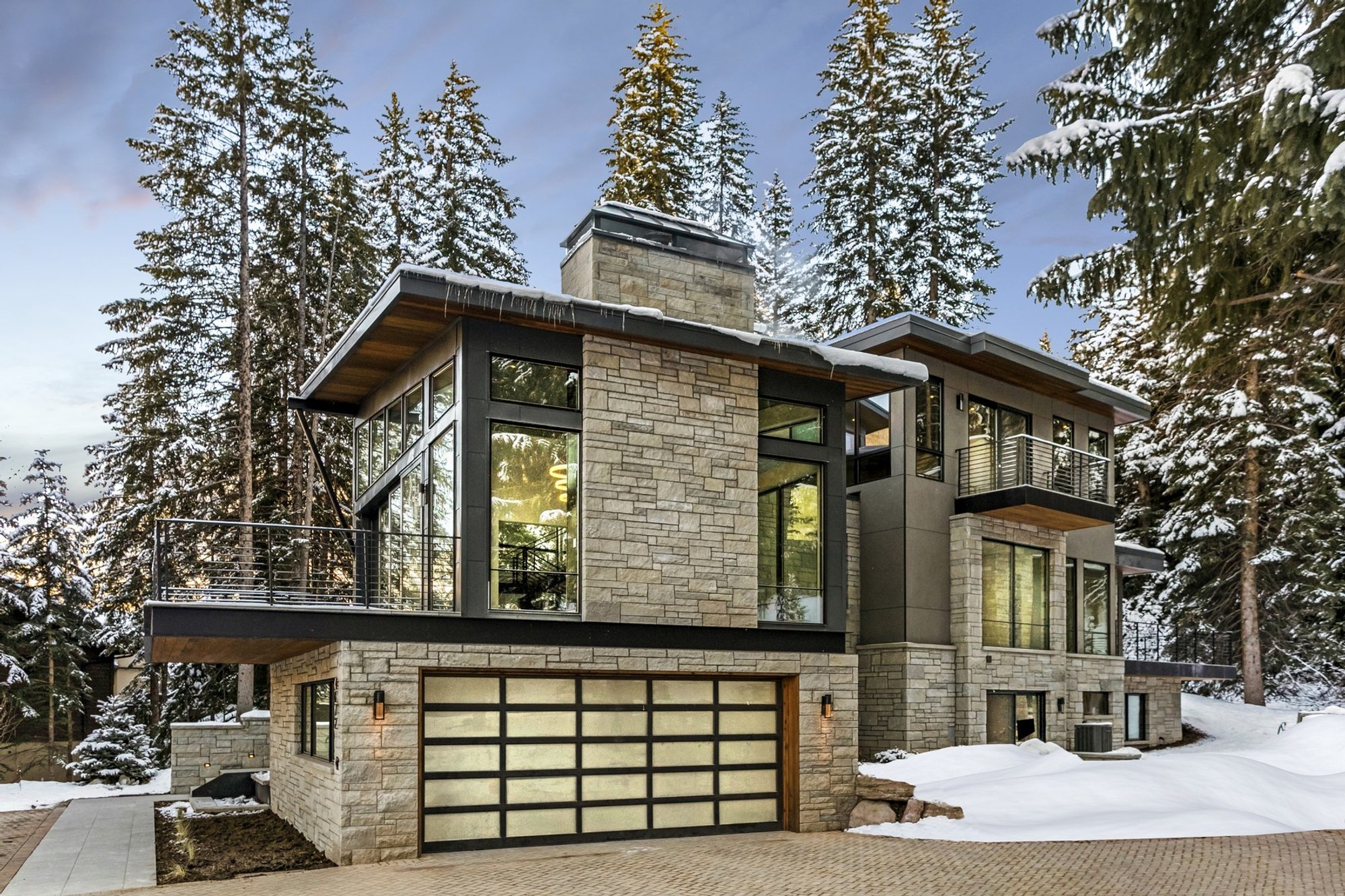 Modern mountainside home design with gray stone, gray fiber cement and black metal siding.