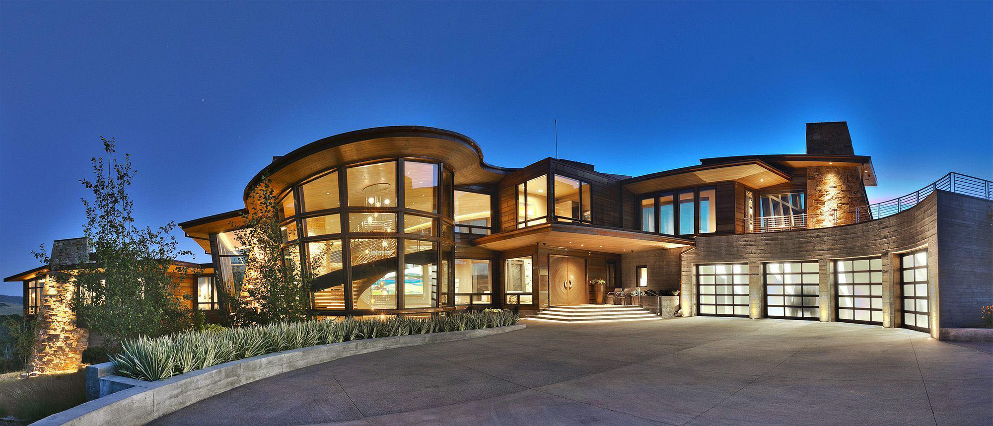 Custom modern home with a mix of wood and stone siding. Huge floor to ceiling windows. Wood soffits.