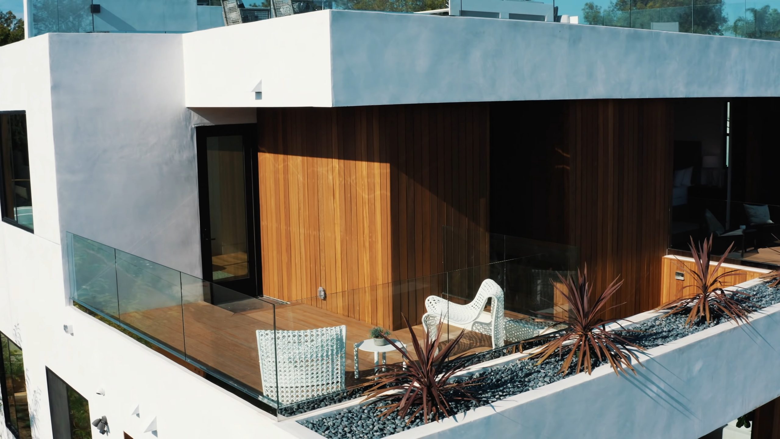Modern home using a combination of smooth stucco and vertical wood siding with glass railings.