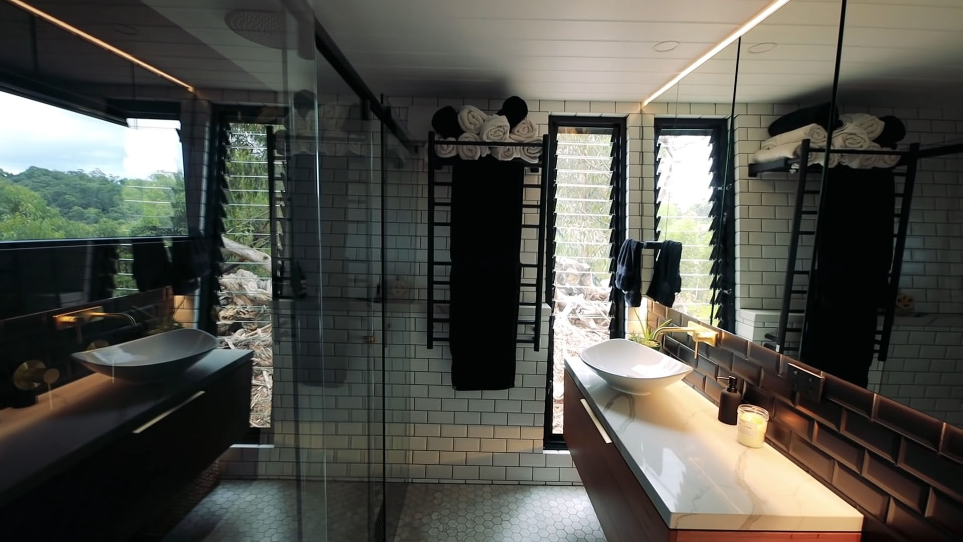 Believe it or not this beautiful luxury bathroom featuring a double shower with glass doors, toilet, vanity with bowl sink and storage is found in a Tiny House.