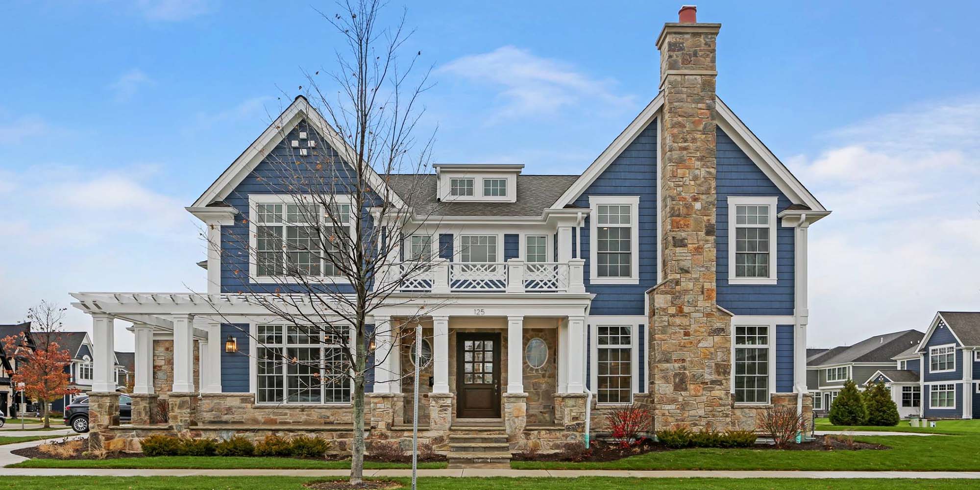 Custom home with blue siding, real stone veneer and coffee bean stained wood front door.