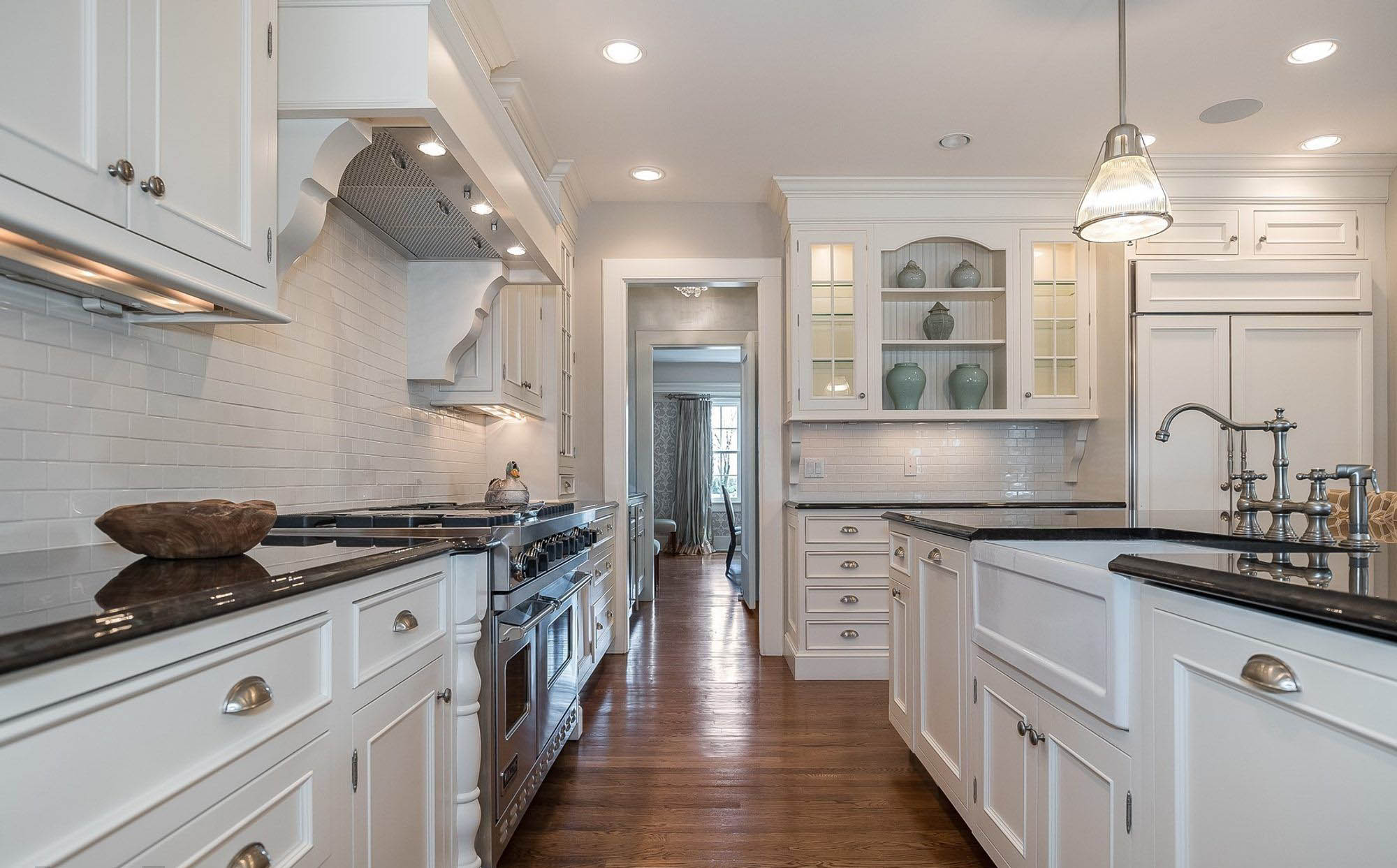 beautiful all white kitchen with black granite countertops and a white farmhouse sink