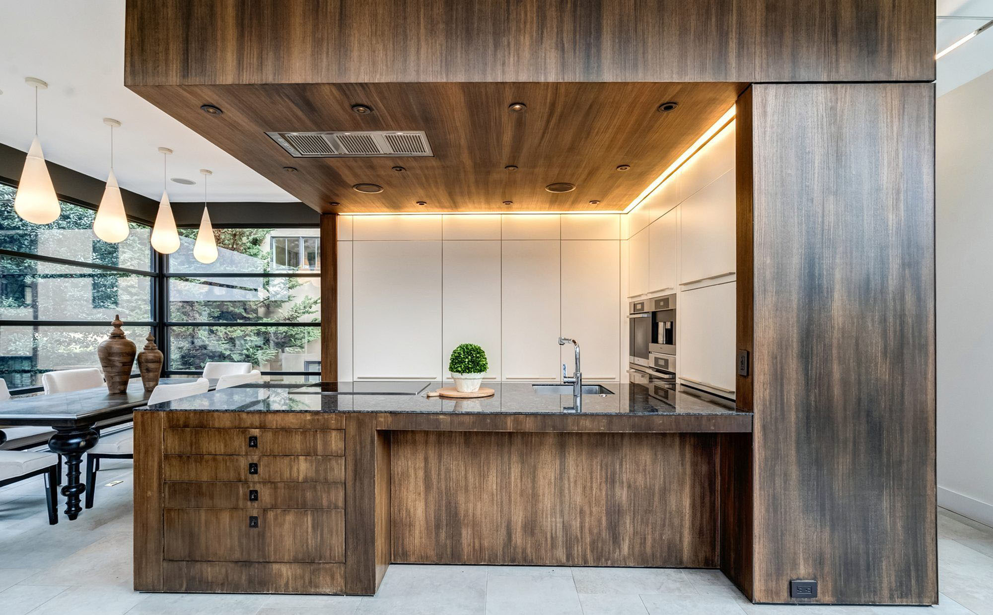 Modern kitchen with drop ceiling finished with wood paneling. Matching wood peninsula island with black granite.