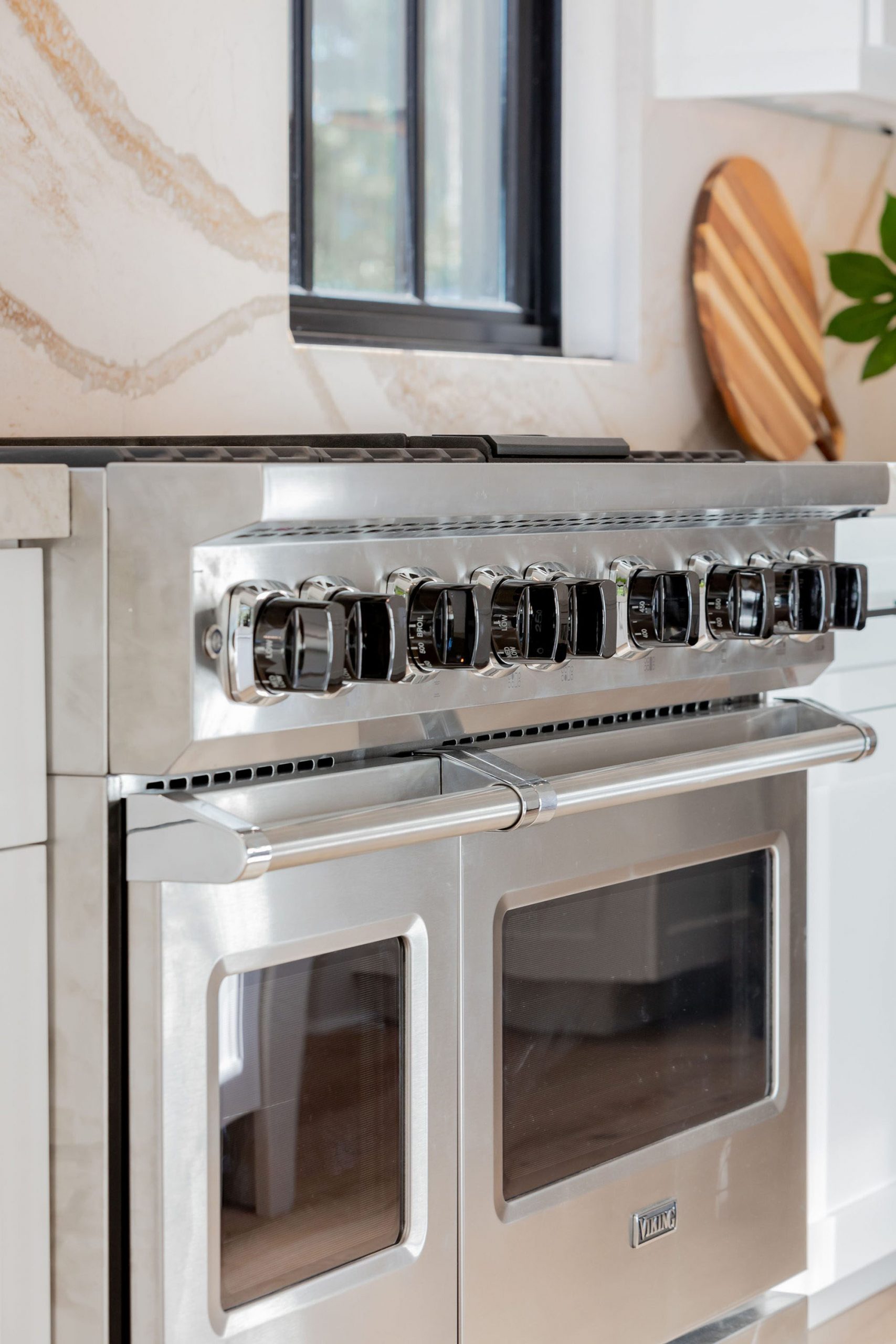 Closeup of a stainless steel Viking range with dual ovens, 6 burners and black knobs.