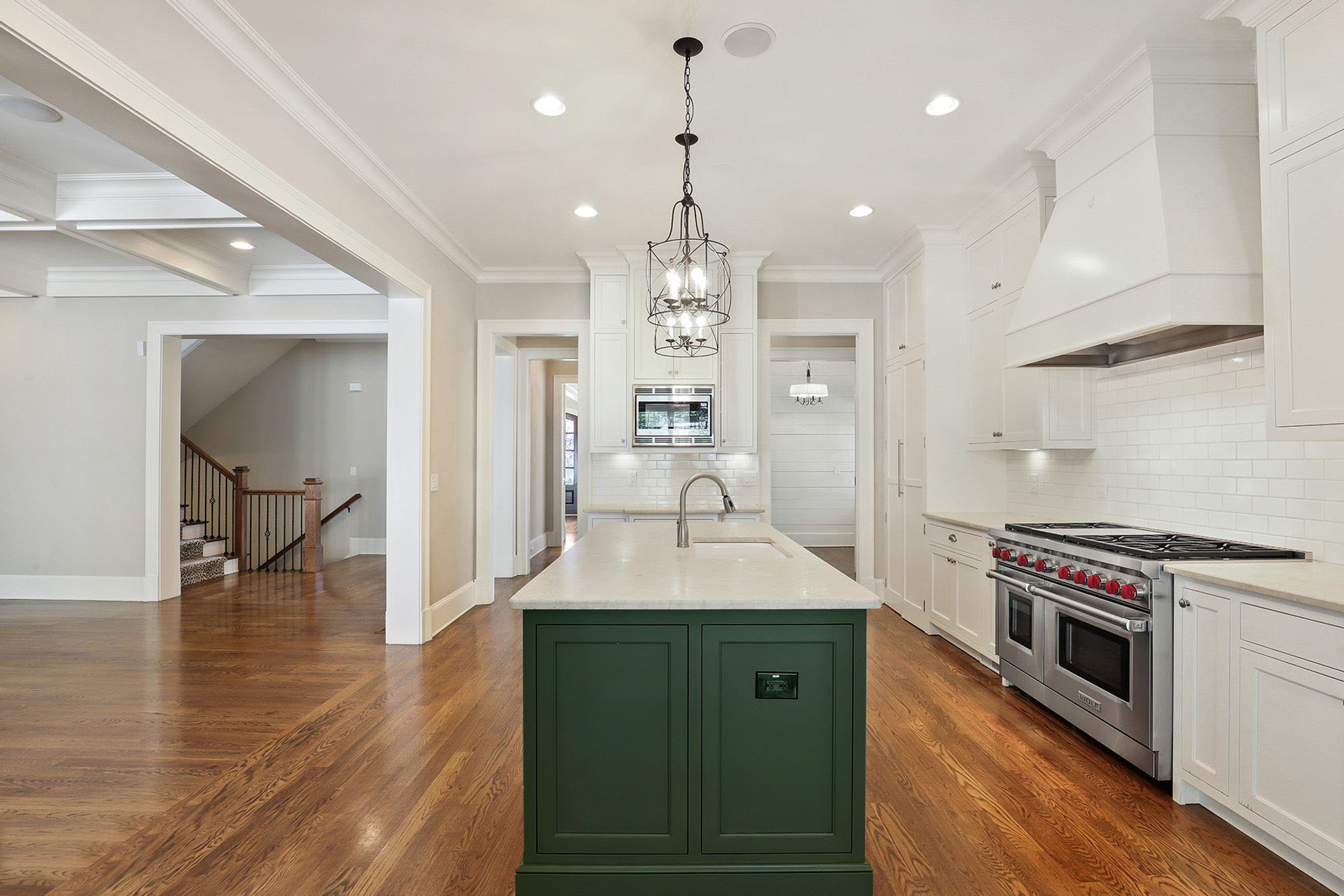 White kitchen cabinets with a forest green center island.