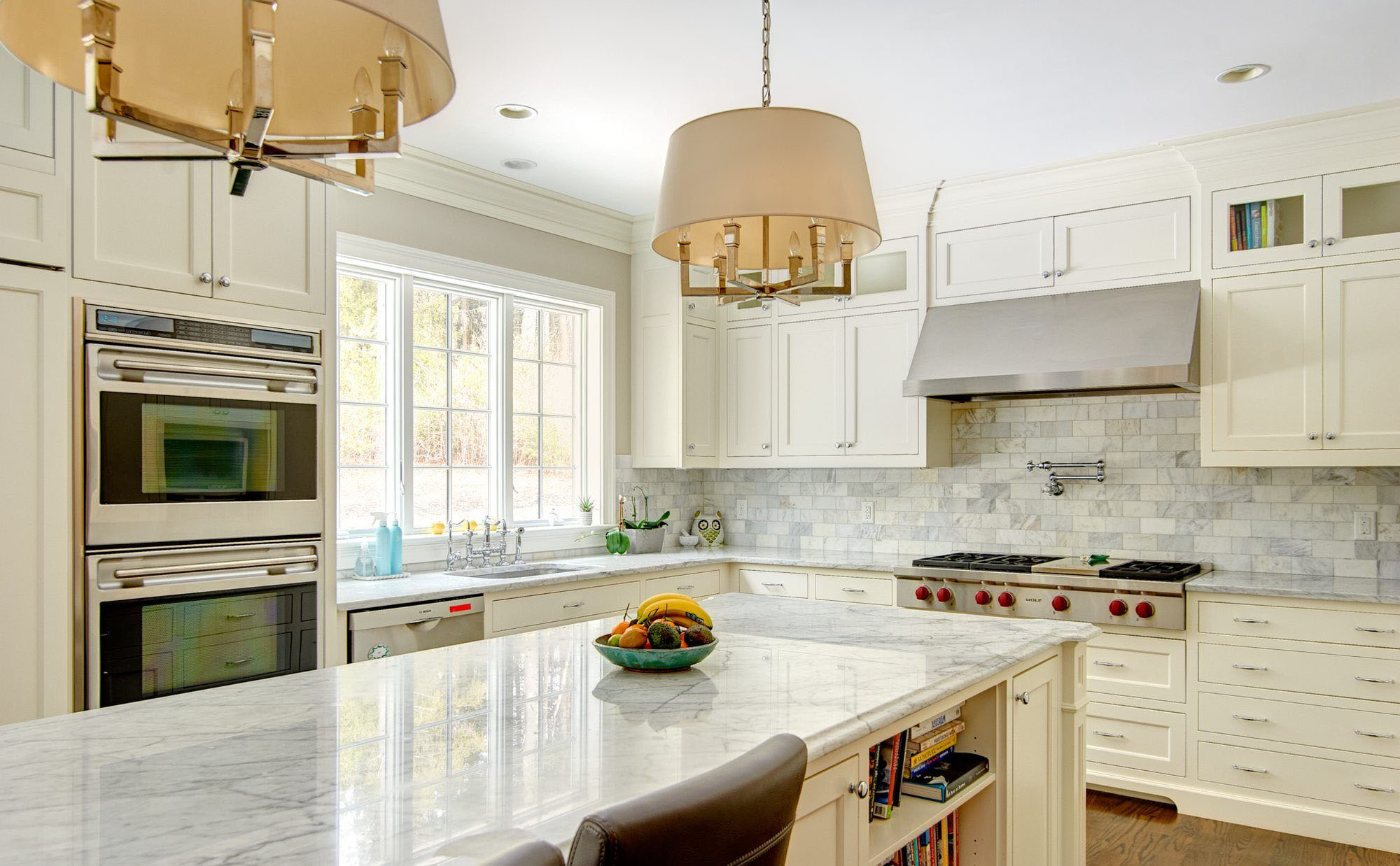 Cream kitchen cabinets with white marble countertops.