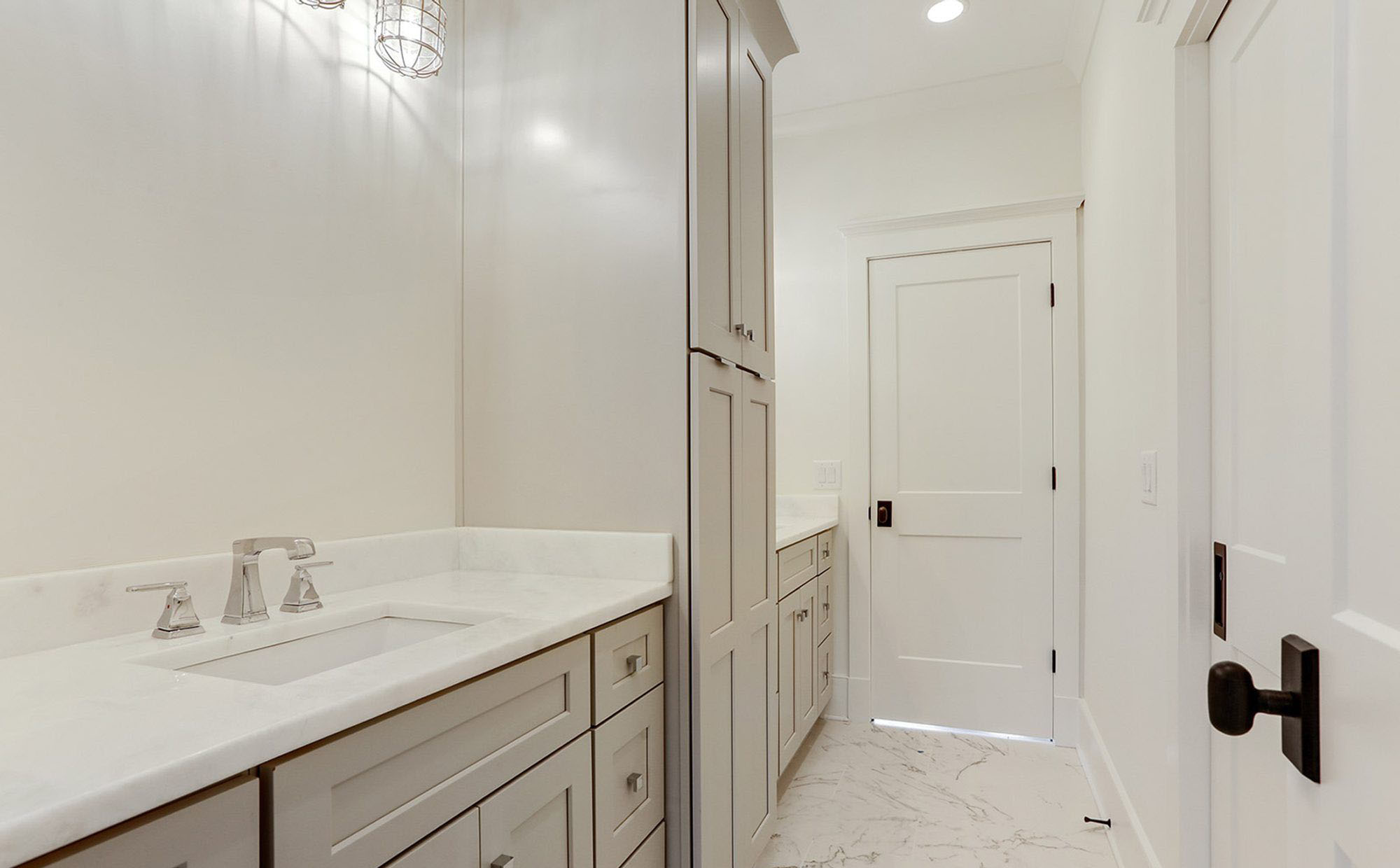 Light gray shaker style bath cabinets with white marble.