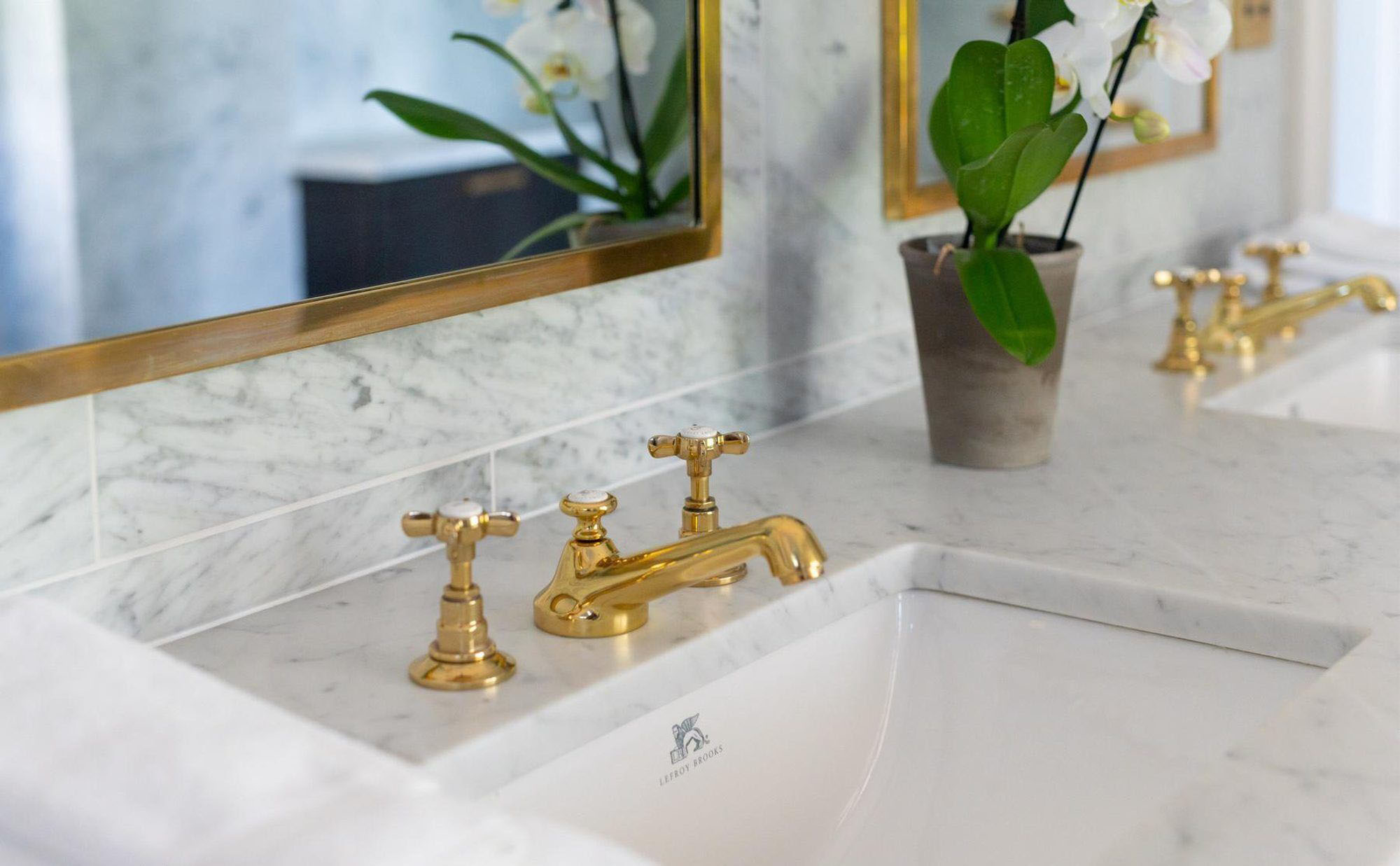 Closeup of a gold bathroom sink faucet with marble countertop.