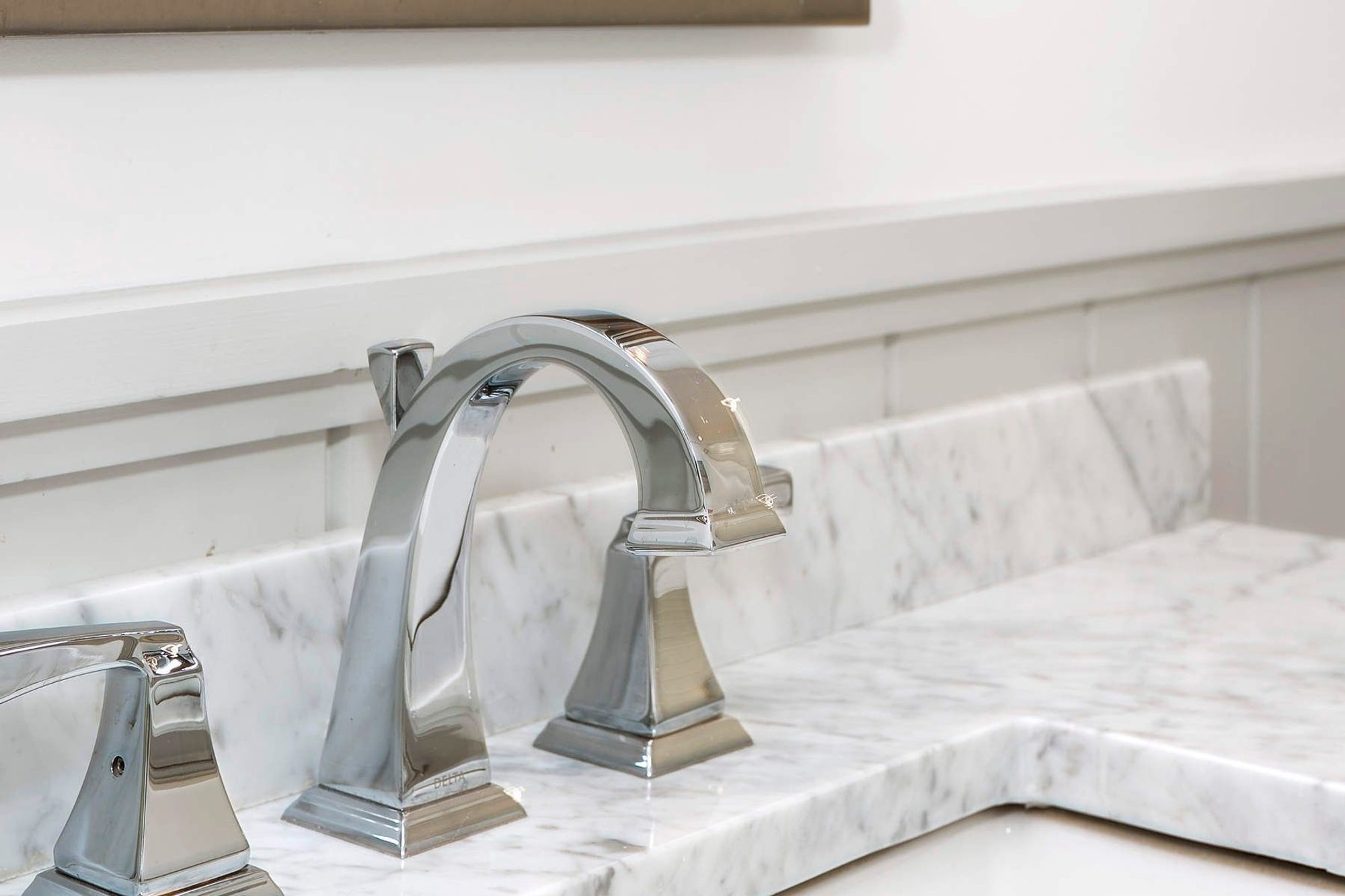 Closeup of a Delta chrome bathroom faucet with marble counter.