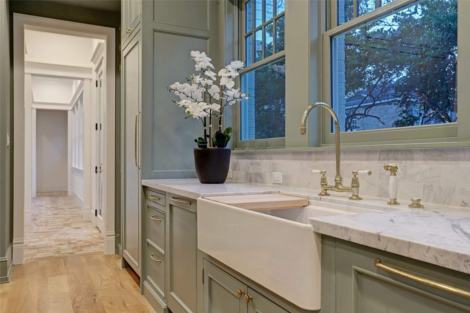 Pale green cabinets with a white farmhouse sink and marble countertops. how to care for marble countertops. 