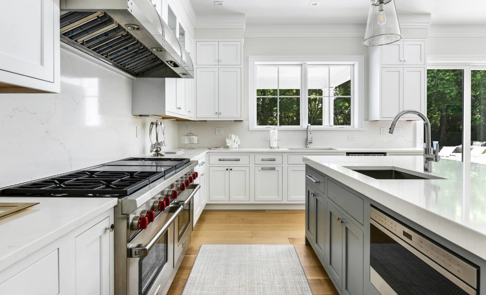 Beautiful kitchen with two tone white and gray cabinets. Marble quartz countertops with matching solid slab backsplash.